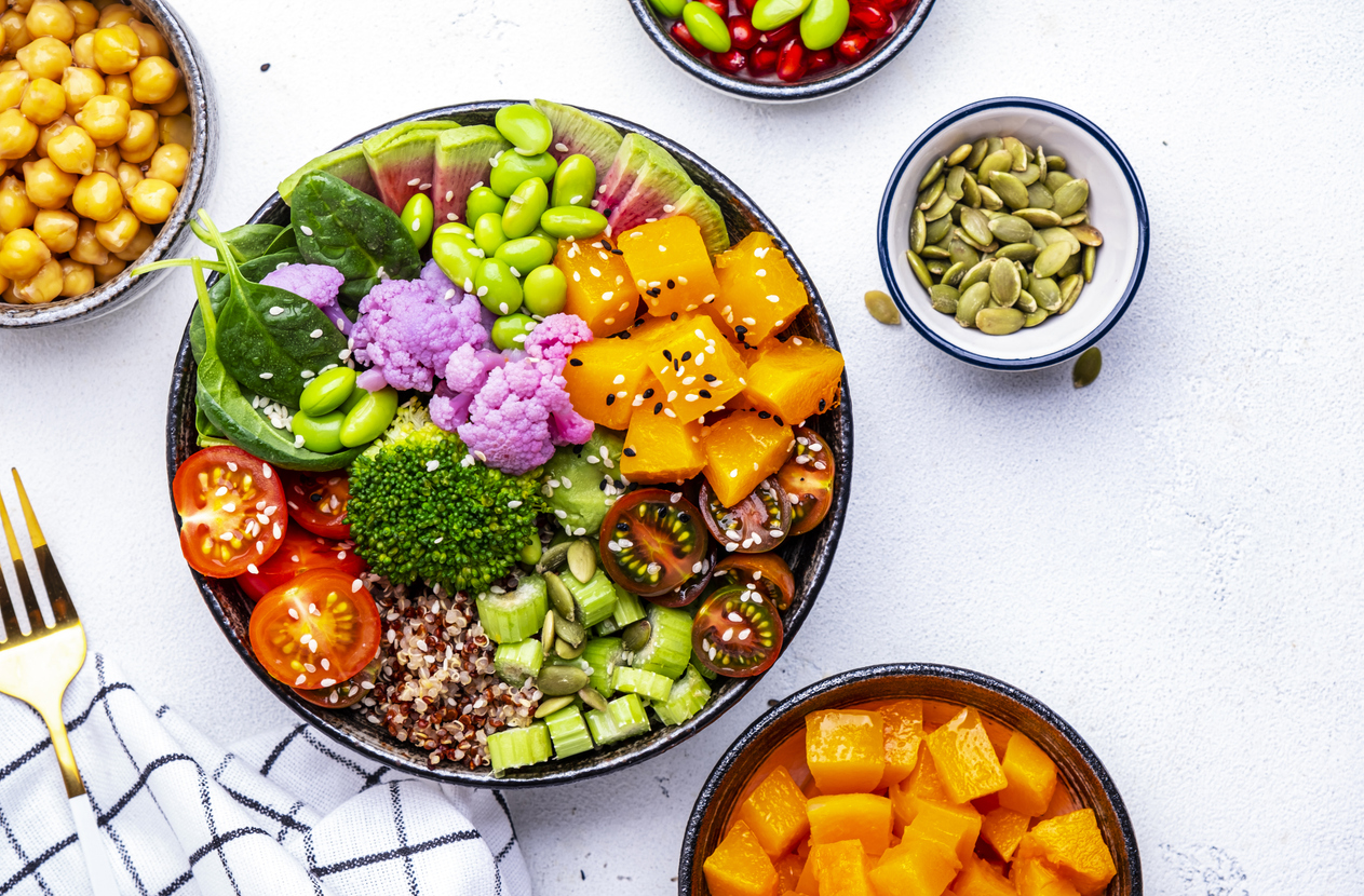 Vegan Buddha Bowl για ισορροπημένη διατροφή με γλυκοπατάτα, quinoa, ντομάτες, σπανάκι, σέλινο, edamame, tofu, μπρόκολο και σπόρους, λευκό φόντο, κάτοψη